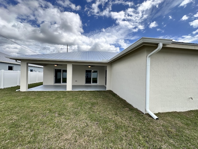 back of property featuring a patio, fence, a ceiling fan, a lawn, and stucco siding