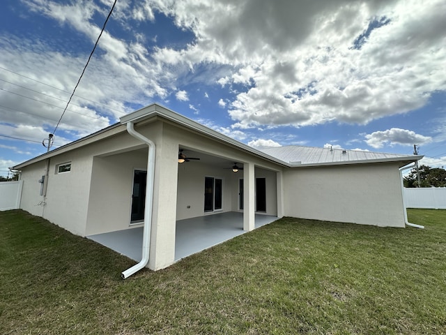 back of house featuring ceiling fan, a yard, and fence