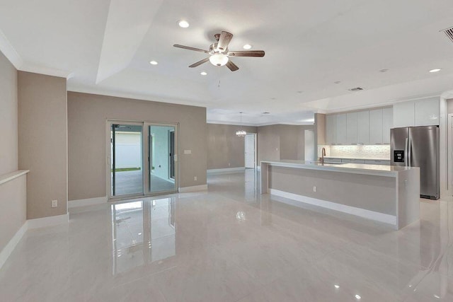 kitchen featuring baseboards, decorative backsplash, modern cabinets, stainless steel refrigerator with ice dispenser, and a sink