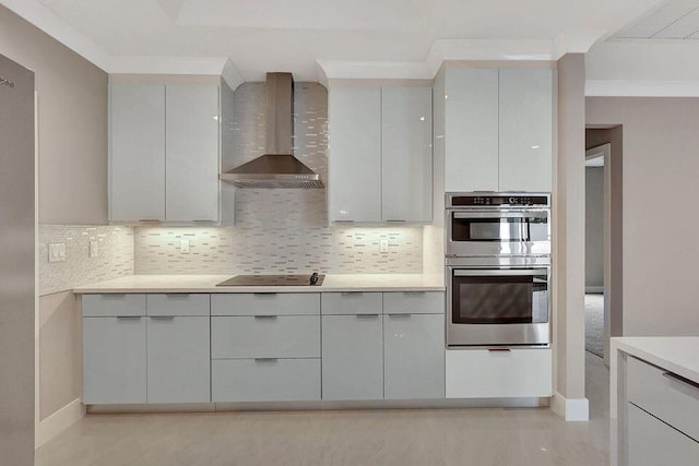 kitchen with tasteful backsplash, black electric stovetop, light countertops, stainless steel double oven, and wall chimney range hood