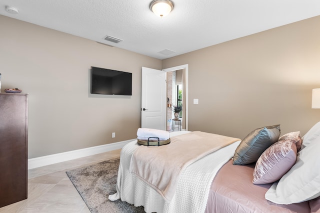 bedroom with visible vents, a textured ceiling, and baseboards