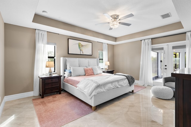 bedroom with access to exterior, baseboards, and a raised ceiling