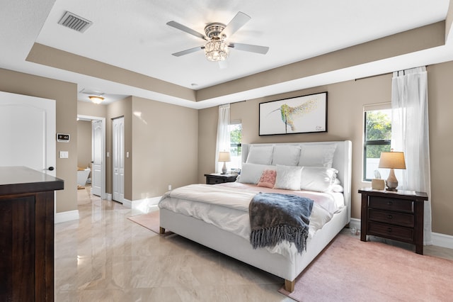 bedroom featuring marble finish floor, baseboards, visible vents, and a tray ceiling