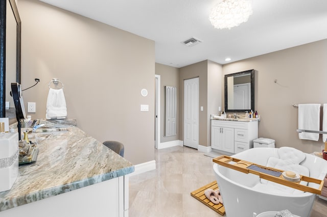 bathroom with baseboards, visible vents, a freestanding bath, vanity, and a closet