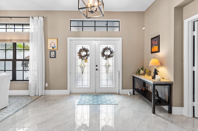 entryway with marble finish floor, baseboards, a notable chandelier, and french doors