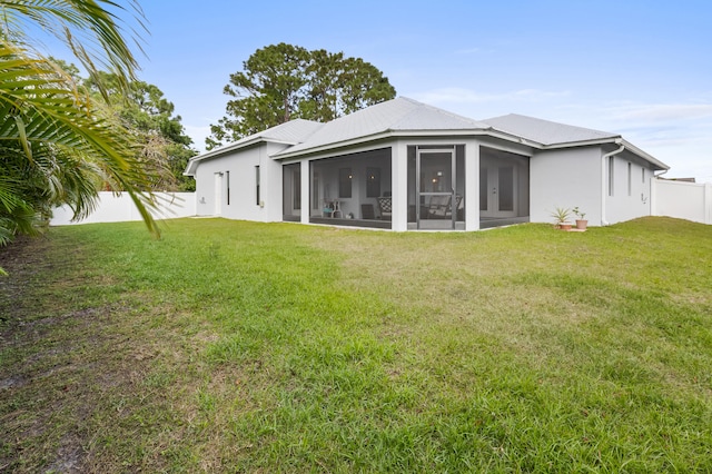 rear view of house with a sunroom, a fenced backyard, and a yard