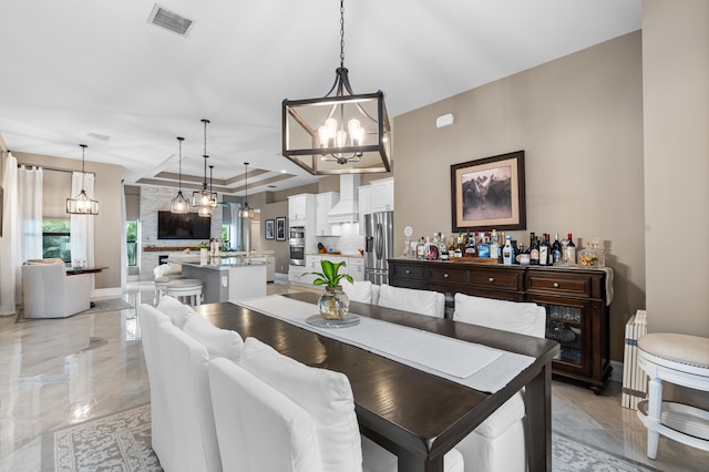 dining space with baseboards, a raised ceiling, visible vents, and an inviting chandelier