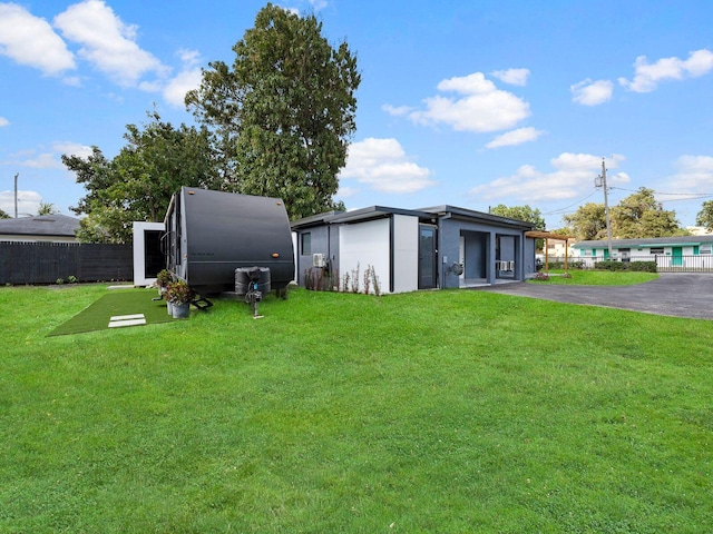 view of outbuilding with aphalt driveway, an attached garage, and fence