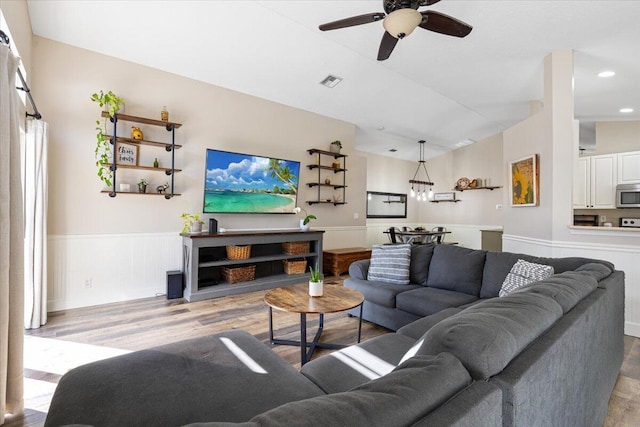 living room with visible vents, a wainscoted wall, wood finished floors, ceiling fan with notable chandelier, and recessed lighting