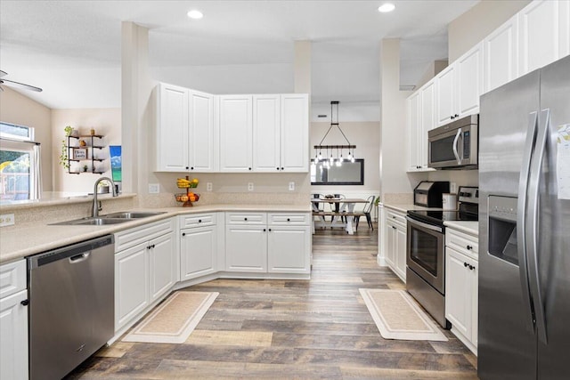 kitchen with stainless steel appliances, wood finished floors, a sink, and white cabinets