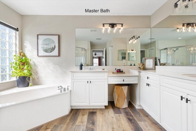 bathroom featuring vanity, wood finished floors, a shower stall, and a bath