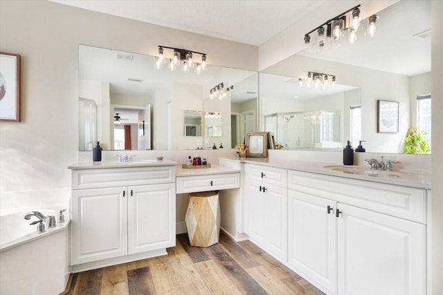 full bathroom featuring a garden tub, a stall shower, ceiling fan, vanity, and wood finished floors