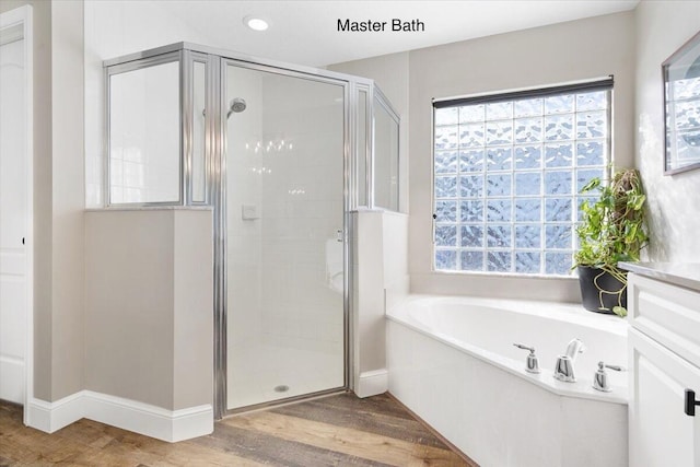 bathroom with a bath, a shower stall, baseboards, and wood finished floors