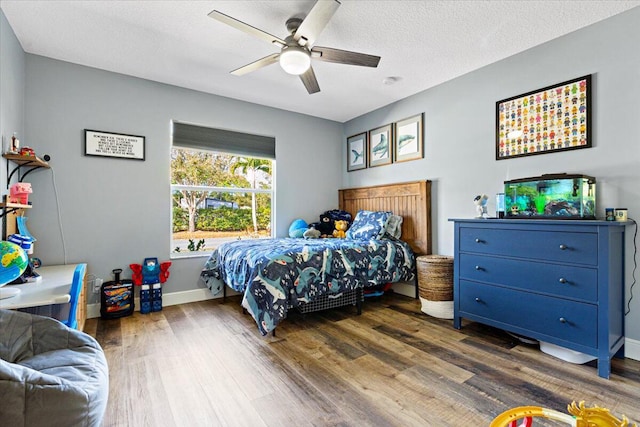 bedroom with a textured ceiling, ceiling fan, wood finished floors, and baseboards