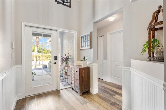 entryway featuring light wood-type flooring, a decorative wall, and wainscoting