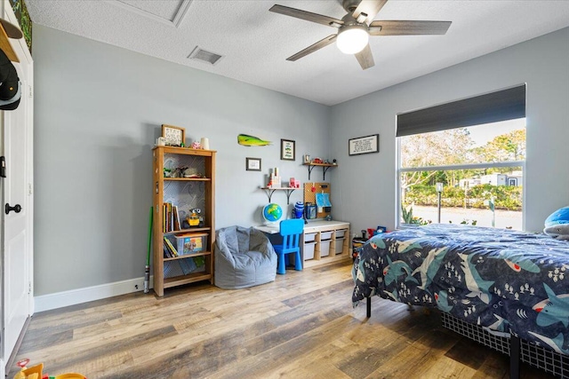 bedroom featuring visible vents, a ceiling fan, a textured ceiling, wood finished floors, and baseboards