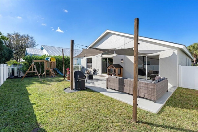 rear view of property featuring a lawn, a fenced backyard, a patio area, a playground, and stucco siding