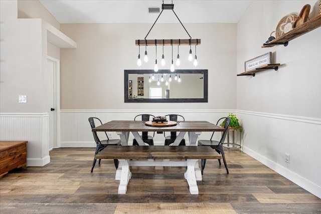 dining room featuring a wainscoted wall, visible vents, and wood finished floors