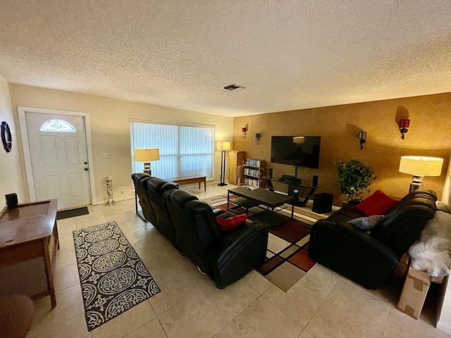 living room featuring light tile patterned floors, visible vents, and a textured ceiling