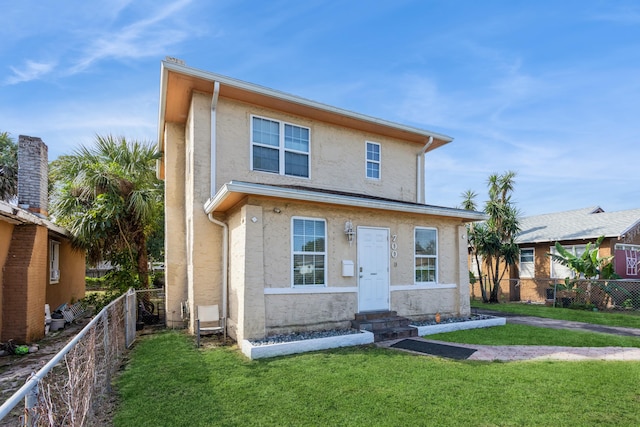 view of front of home featuring entry steps, a fenced backyard, a front lawn, and stucco siding