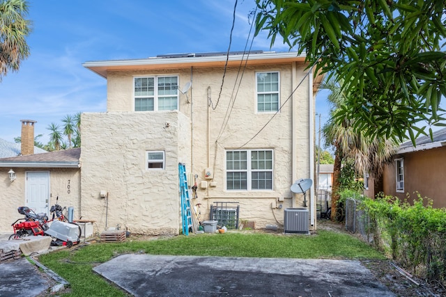 rear view of property with central AC unit, fence, a lawn, stucco siding, and a patio area