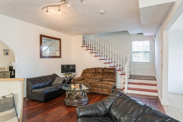 living area featuring stairs, dark wood-style flooring, arched walkways, and baseboards