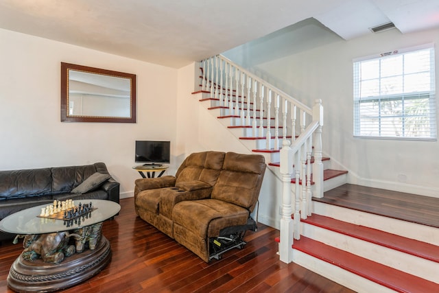 living area with baseboards, visible vents, stairway, and dark wood-type flooring