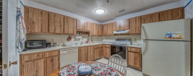 kitchen with under cabinet range hood, white appliances, a sink, visible vents, and light countertops