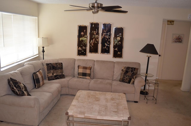 living area featuring light carpet and a ceiling fan