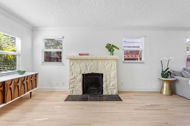 living room with crown molding, light wood-style floors, a fireplace, and a textured ceiling