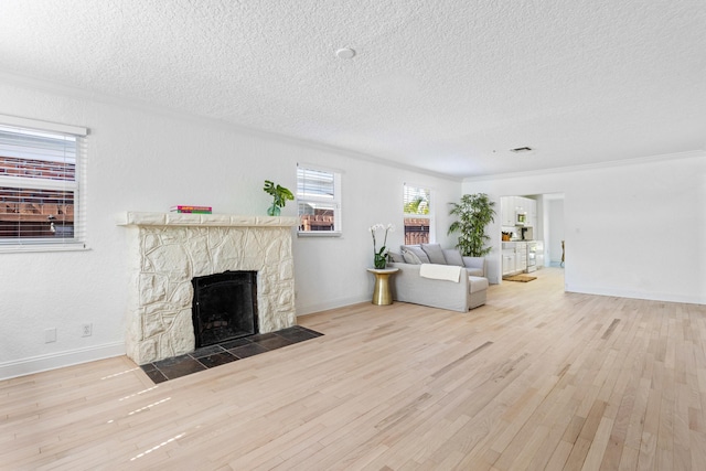 unfurnished living room with light wood-type flooring, a fireplace, and a textured ceiling