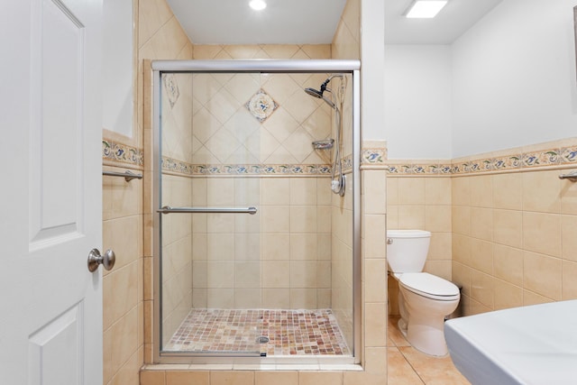 full bath featuring a shower stall, toilet, and tile walls