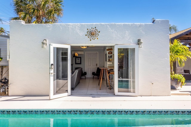 back of property with an outbuilding, an exterior structure, an outdoor pool, and stucco siding