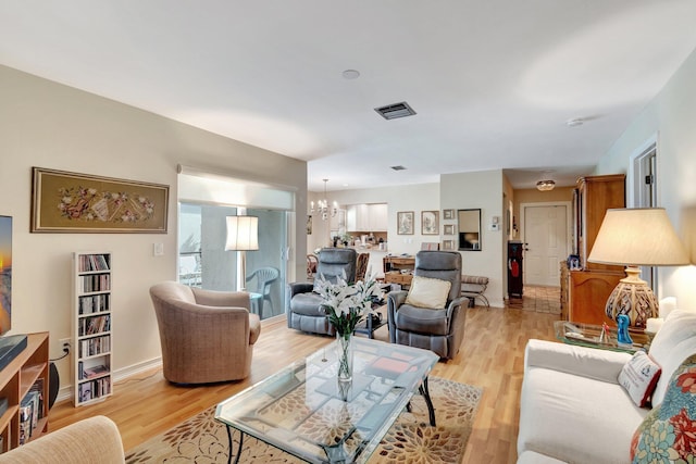 living room with a chandelier, baseboards, visible vents, and light wood finished floors