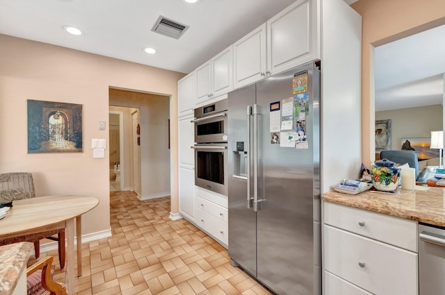 kitchen with recessed lighting, visible vents, appliances with stainless steel finishes, white cabinets, and light stone countertops