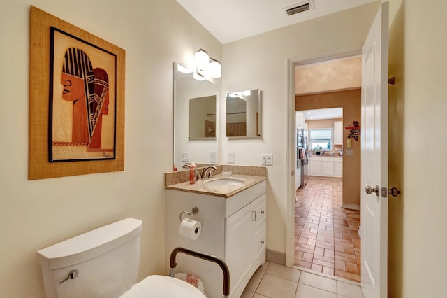 bathroom featuring baseboards, visible vents, toilet, tile patterned floors, and vanity