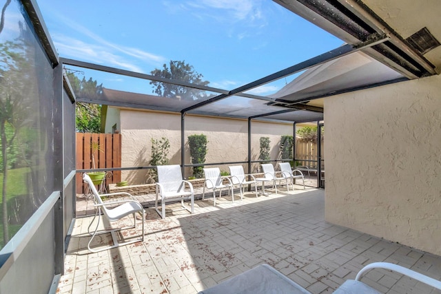 view of patio featuring a lanai and fence