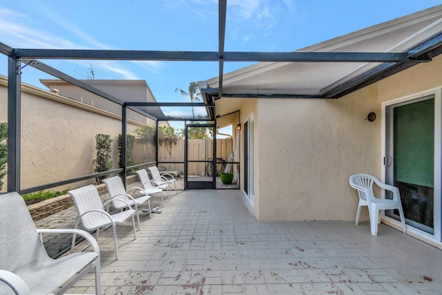 view of patio featuring glass enclosure and fence