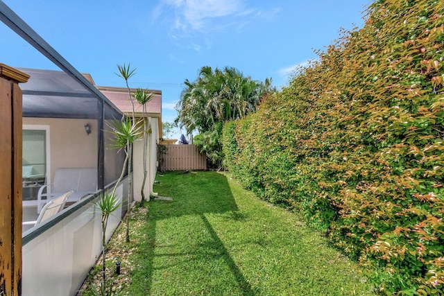 view of yard with a lanai and fence