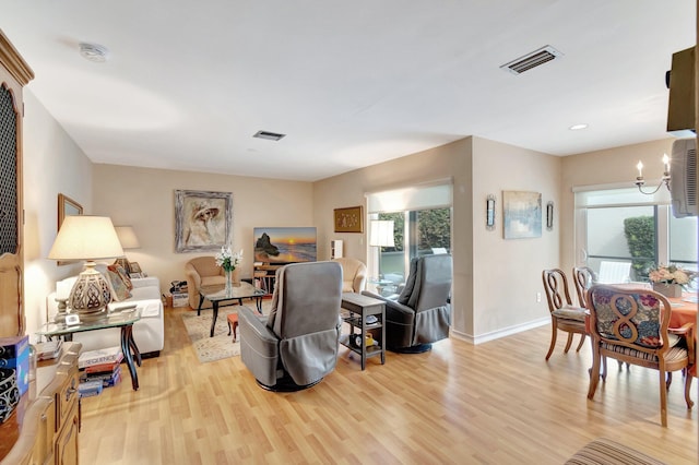 living room featuring a notable chandelier, light wood-style floors, visible vents, and a healthy amount of sunlight