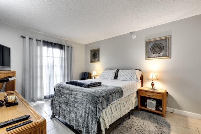 bedroom featuring light tile patterned floors, a textured ceiling, and baseboards