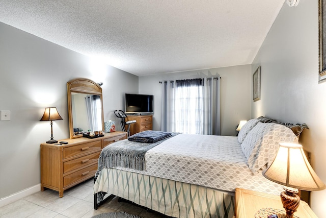 bedroom featuring a textured ceiling, baseboards, and light tile patterned floors