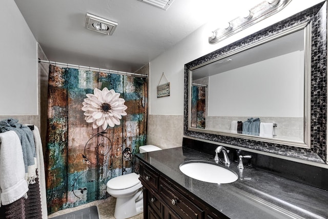 bathroom featuring a wainscoted wall, tile walls, toilet, and vanity