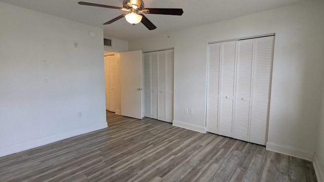 unfurnished bedroom featuring multiple closets, visible vents, and baseboards