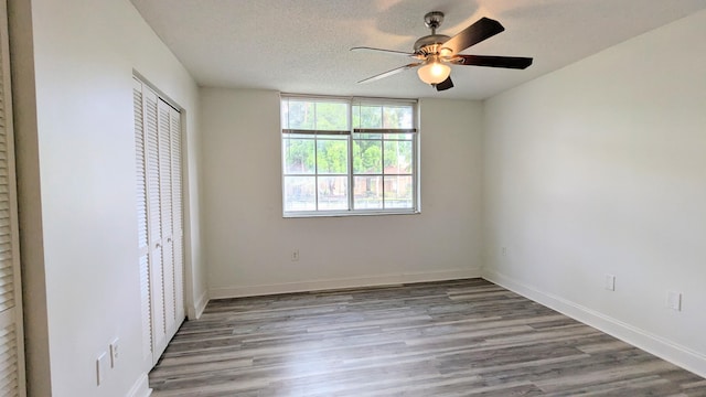 unfurnished bedroom featuring light wood finished floors, a closet, ceiling fan, a textured ceiling, and baseboards