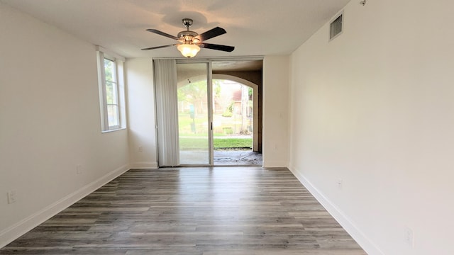 unfurnished room featuring baseboards, plenty of natural light, visible vents, and dark wood-style flooring