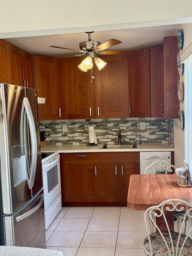 kitchen featuring light countertops, a sink, tasteful backsplash, white appliances, and ceiling fan