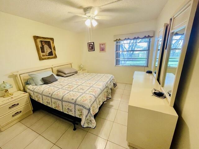 bedroom with light tile patterned flooring, a ceiling fan, and a textured ceiling