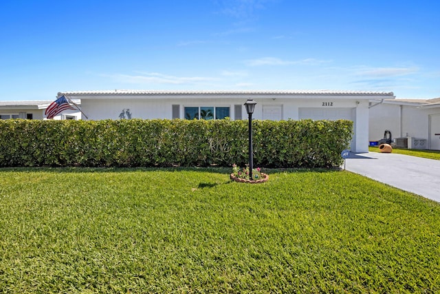 ranch-style home featuring a garage, central AC unit, concrete driveway, and a front yard