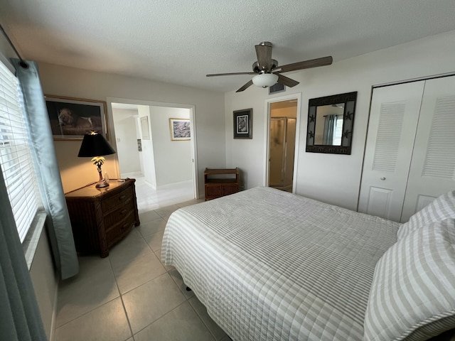 bedroom with a textured ceiling, a closet, light tile patterned flooring, and a ceiling fan